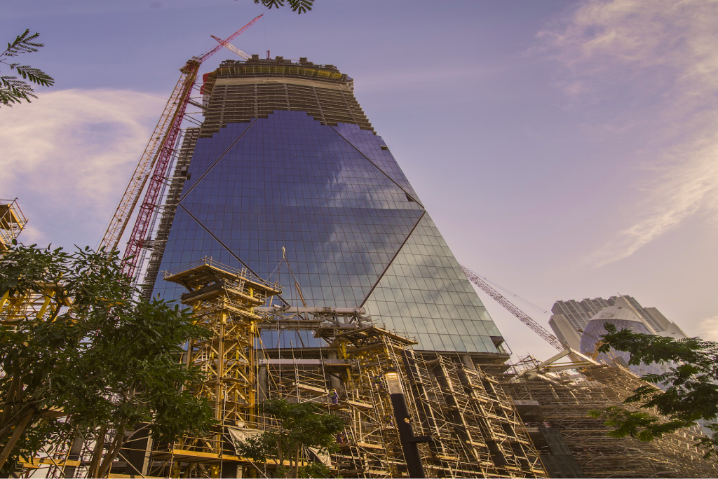 Glass tower under construction against a blue sky